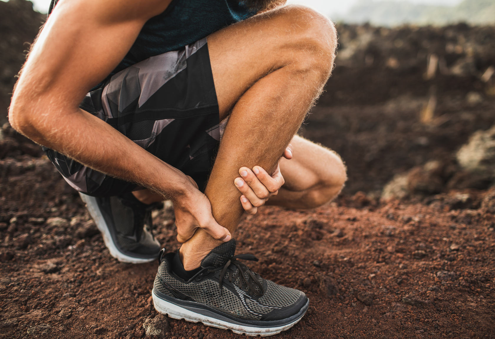 A runner rubs their ankle to relieve pain in the achilles tendon